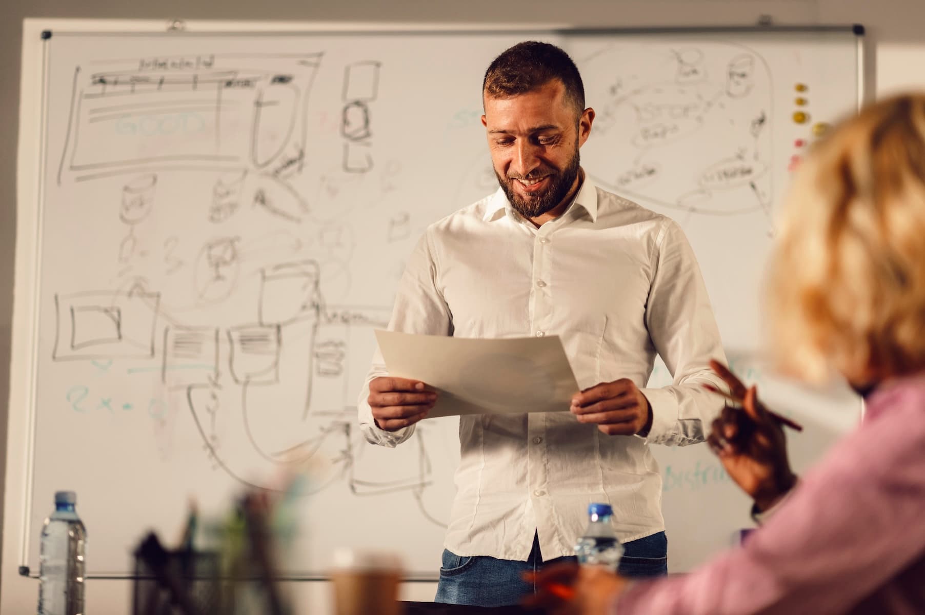 Smiling manager reading report to colleagues in meeting room