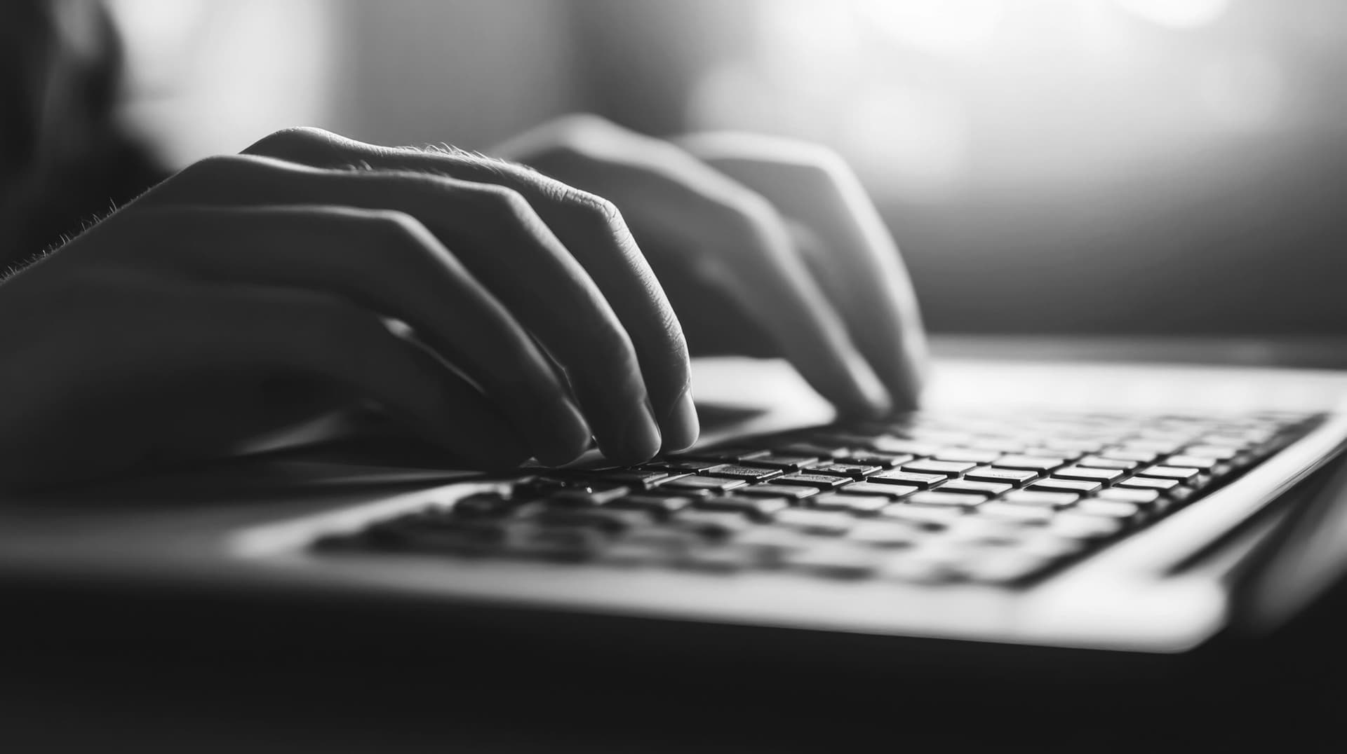 Close-up of Hands Typing on a Laptop Keyboard in Dim Light
